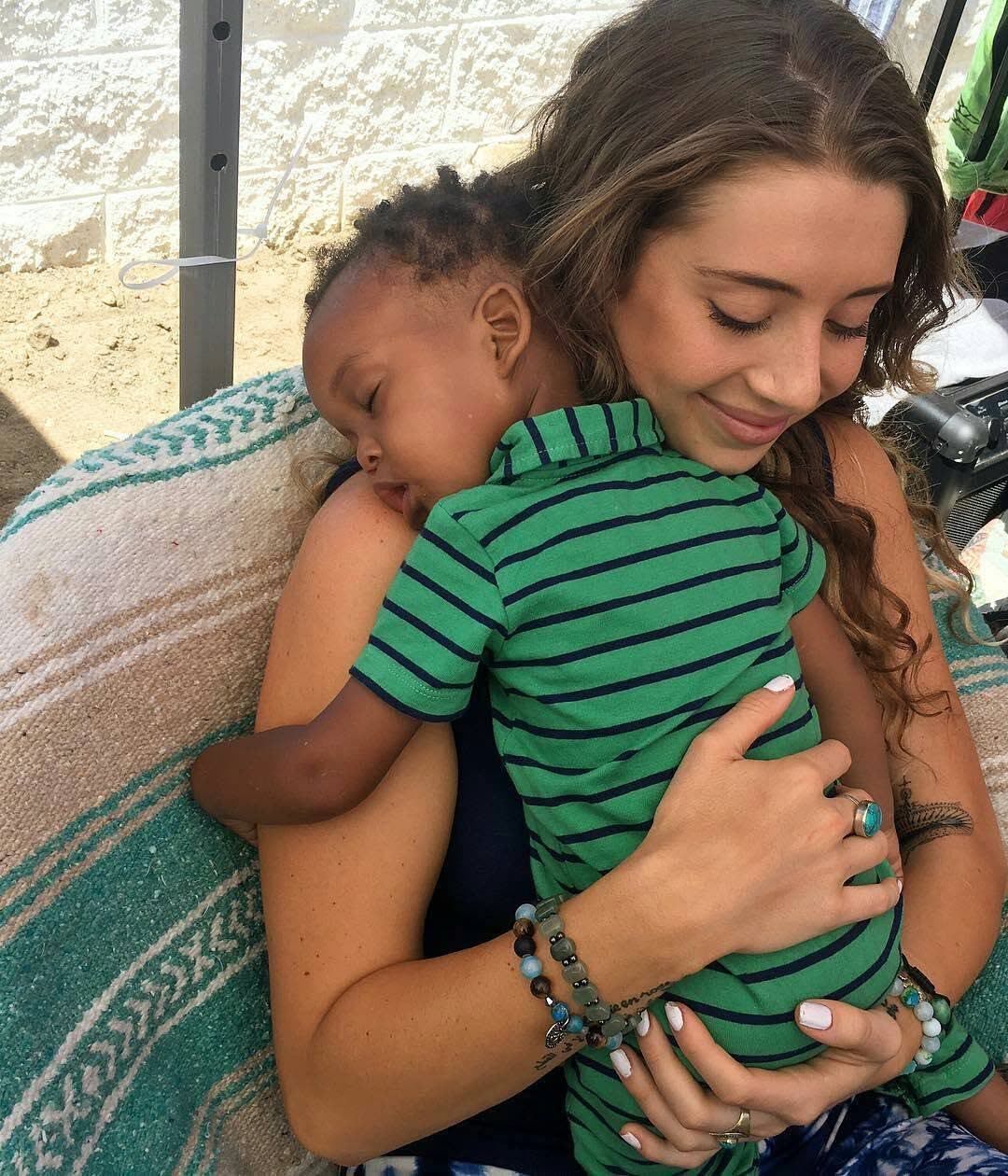 A tender moment of a parent cradling a sleeping child at a gathering.